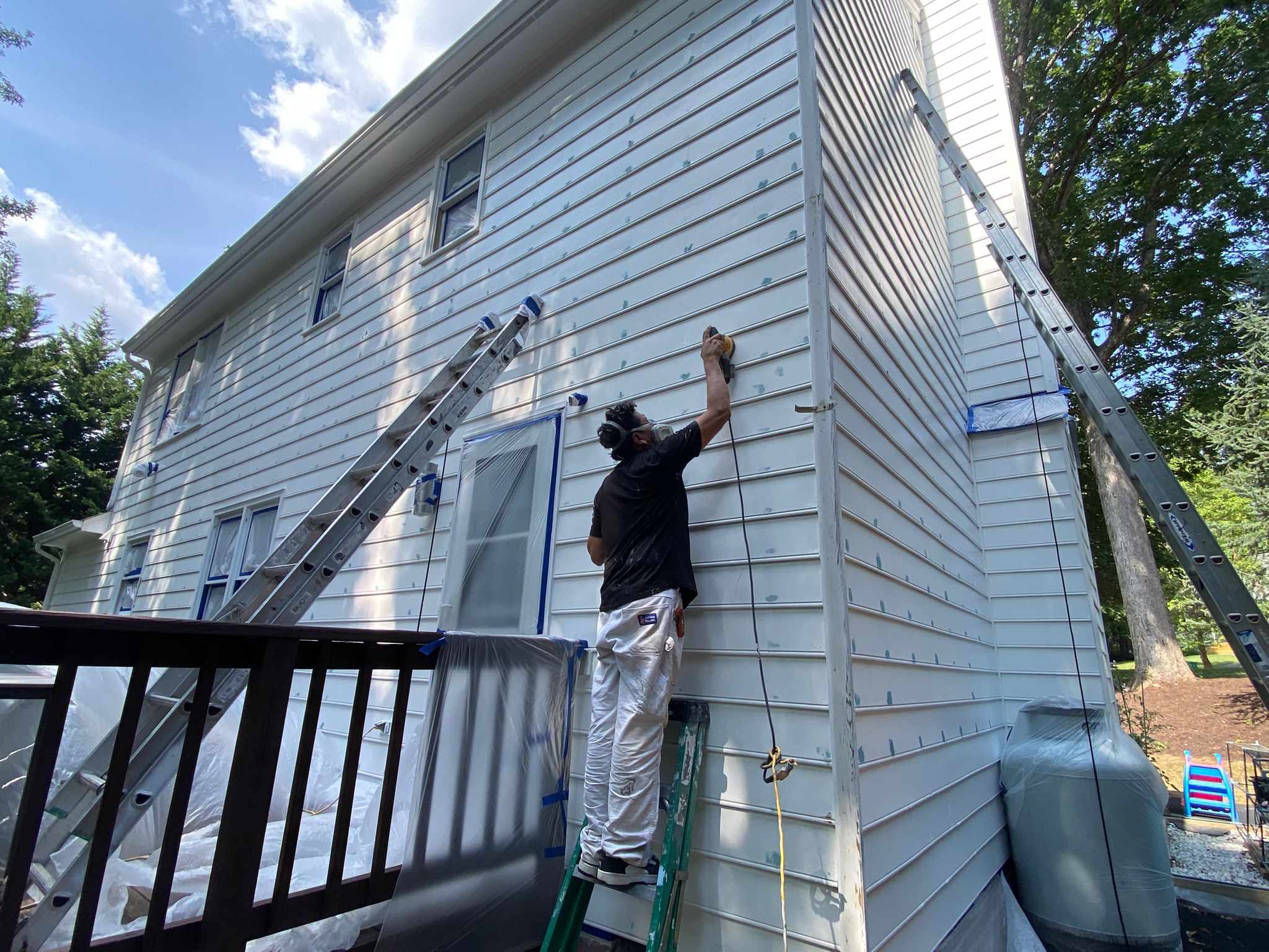 Painters on ladders repainting a two-story home exterior