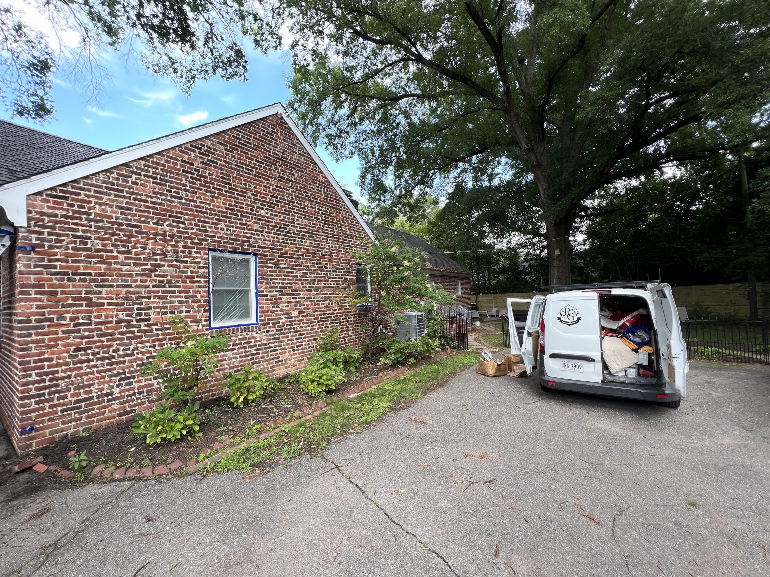 Brick home exterior painting project with work van on site