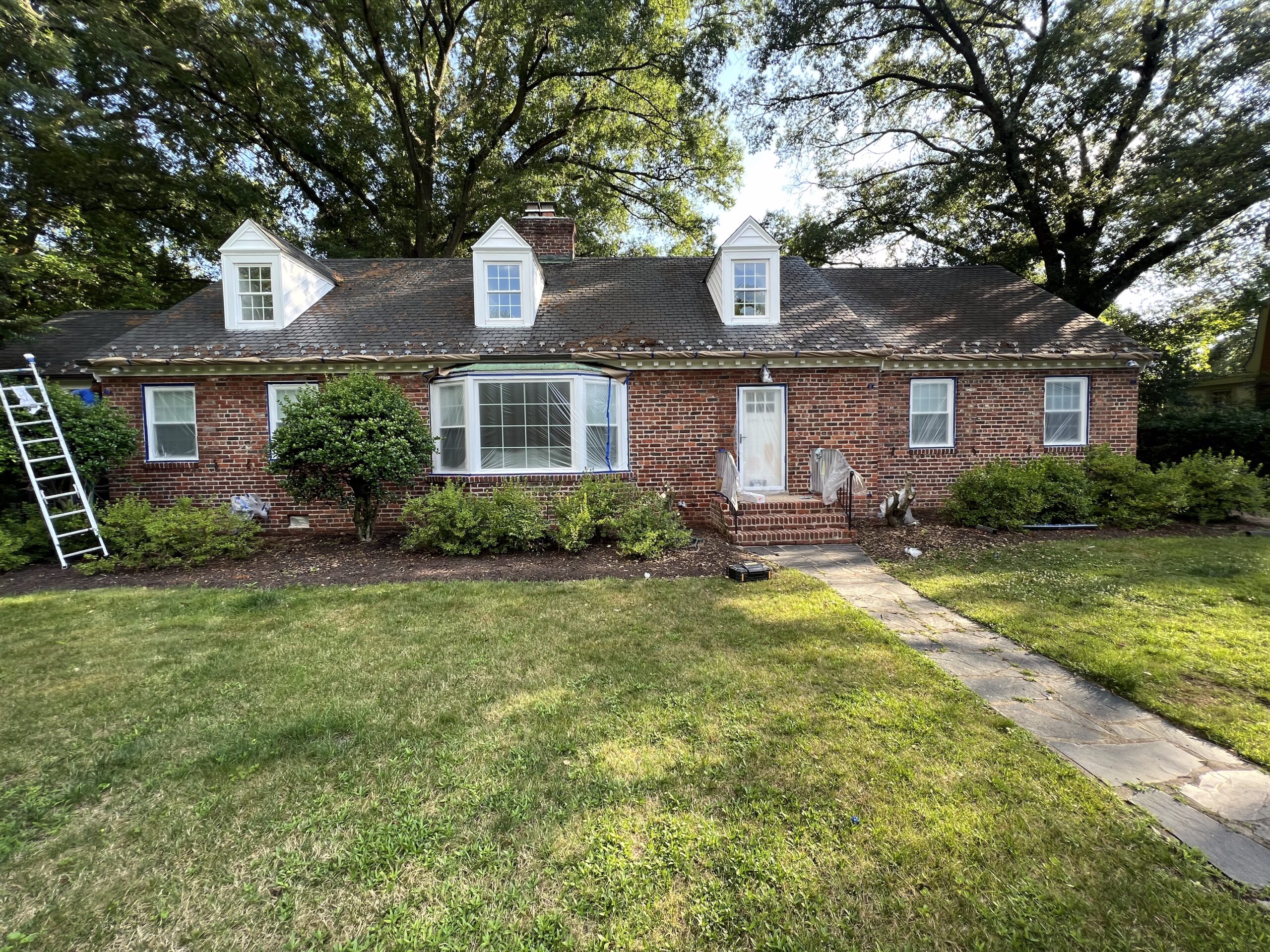 Brick Cape Cod home with freshly painted dormers and trim