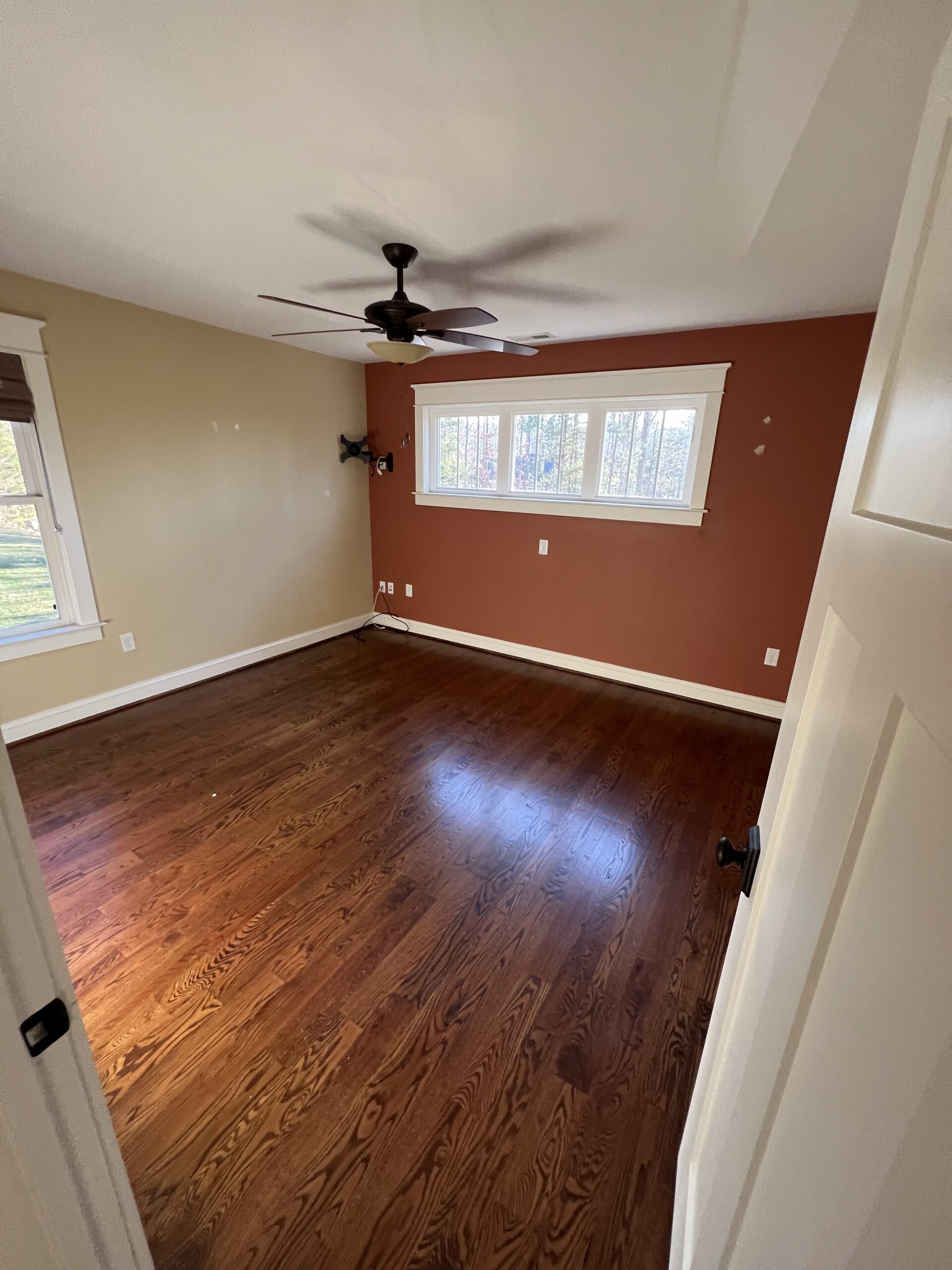Bedroom with red-brown accent wall and hardwood floors
