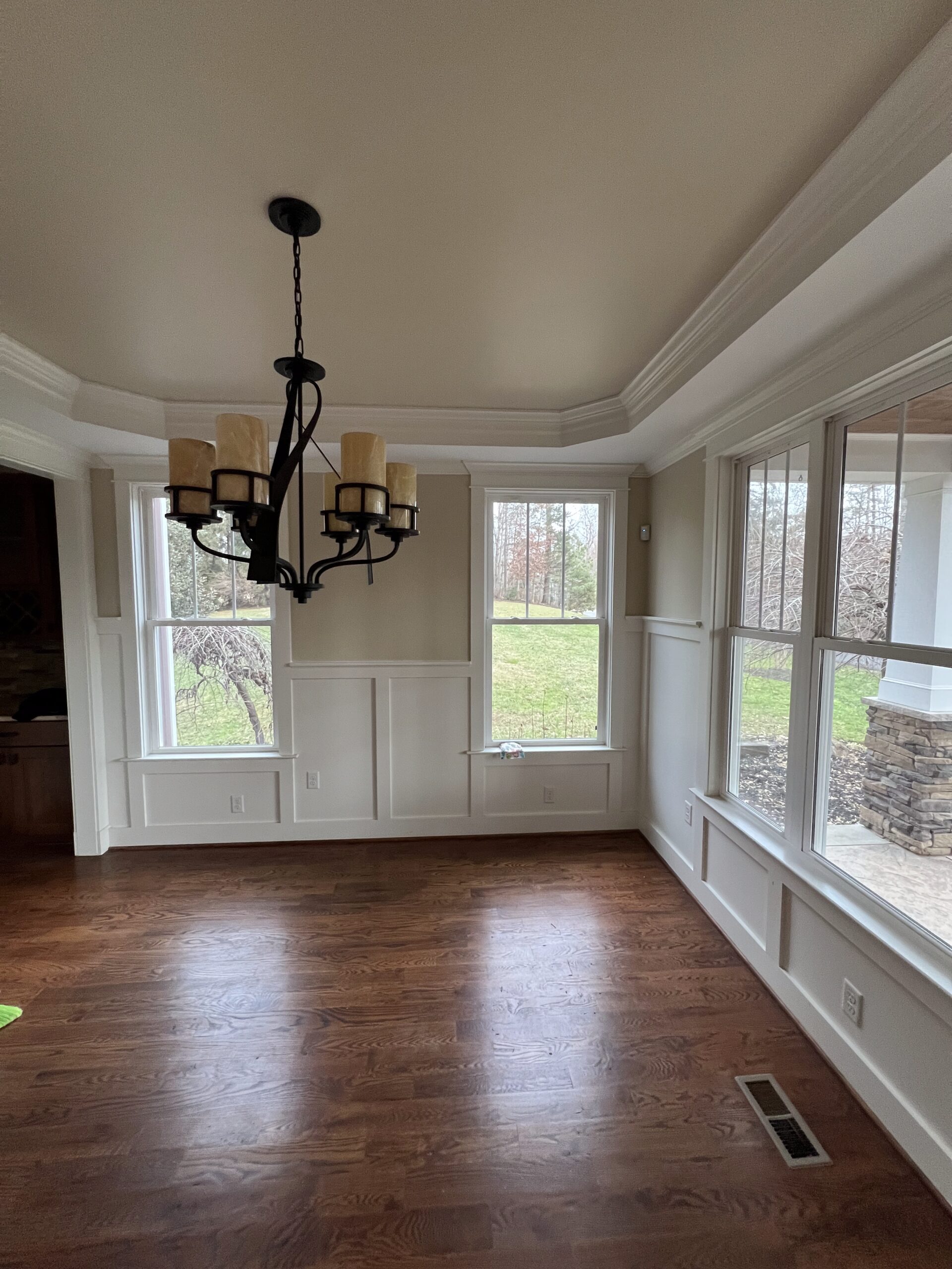 Sunroom with white painted wainscoting and large windows